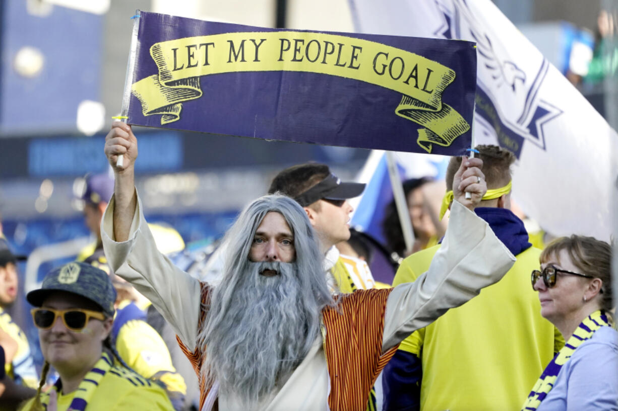 Stephen Mason, dressed as "Soccer Moses," holds up a sign which reads, "Let my people goal" before an MLS soccer match between Nashville SC and New York Red Bulls Sunday, Nov. 7, 2021, in Nashville, Tenn. His face flies on a flag outside the Nashville new stadium and he's often found in the team's supporter section, where its most devoted fans gather.