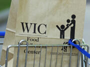 FILE - In this Oct. 3, 2013 file photo, a special supplemental nutrition program for women, infants and children, better known as WIC, bag sits on a shopping cart waiting to be loaded into a recipient's vehicle at a center in Jackson, Miss.  (AP Photo/Rogelio V.