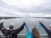 People hold hands and form a link from Washington to Oregon during the Hands Across the Bridge event that celebrates those in any stage of addiction recovery.