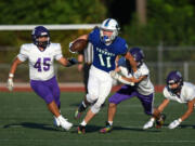 Mountain View's Aiden Nicholson (11) evades tackles from Nooksack Valley defenders in the season-opening football game Friday at McKenzie Stadium.
