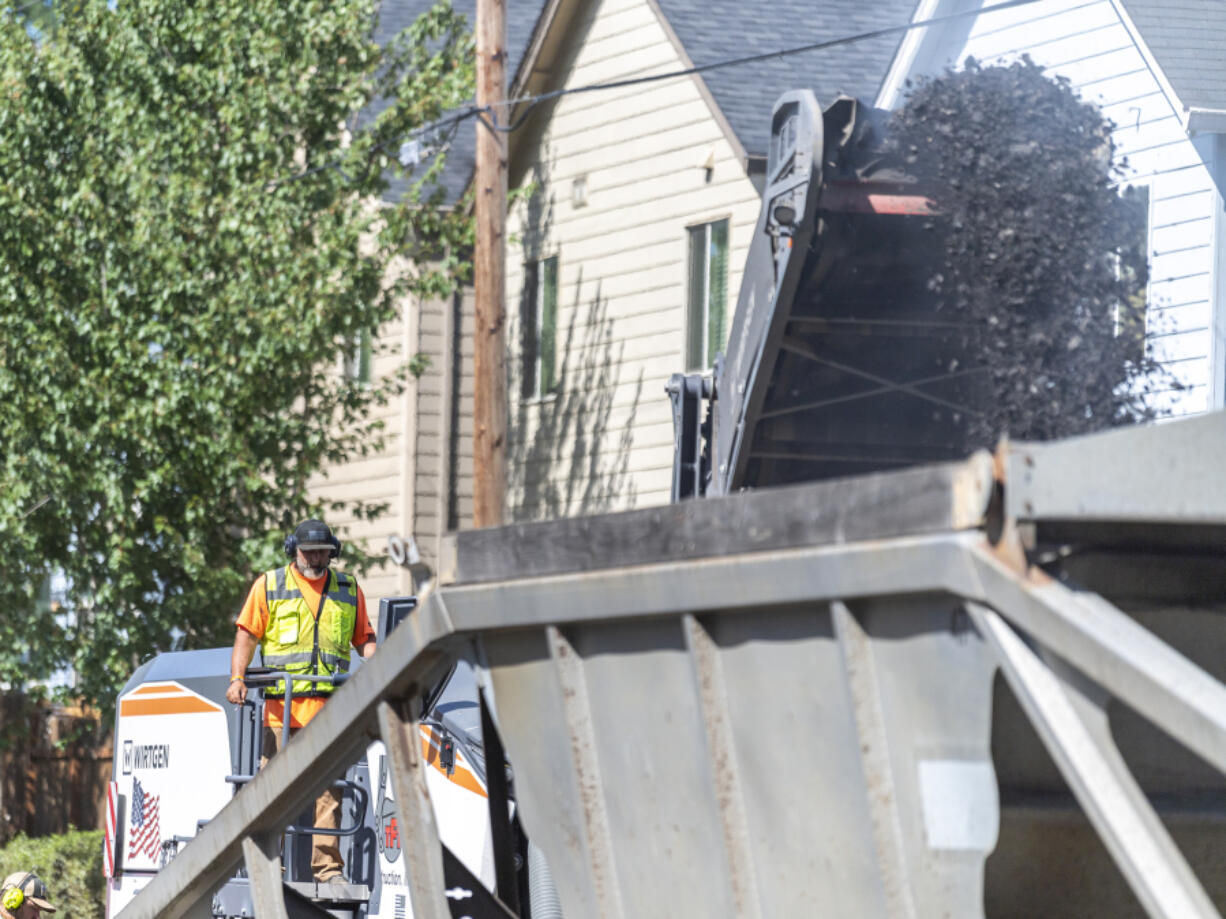 A construction crew uses an asphalt milling machine to tear up the road and put the grindings into a truck Tuesday on Northeast 58th Street. Both the city of Vancouver and Clark County place a large emphasis on preventive work.