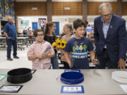 Hockinson Heights Elementary School fifth graders Kevin Brown, with sunflowers from left, Perry Burnham, Charlie O'Donnell Munson-Young, and Bear Ricks, all 10, show Gov. Jay Inslee the recycling area in their cafeteria as he toured their school.