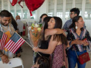 Bibiana Pinon-Hernandez is hugged by family Thursday morning after becoming a naturalized U.S. citizen after emigrating from Mexico. At top, Maria Miramon, from Mexico, also becomes a U.S. citizen during a ceremony at the Pearson Air Museum Hangar.