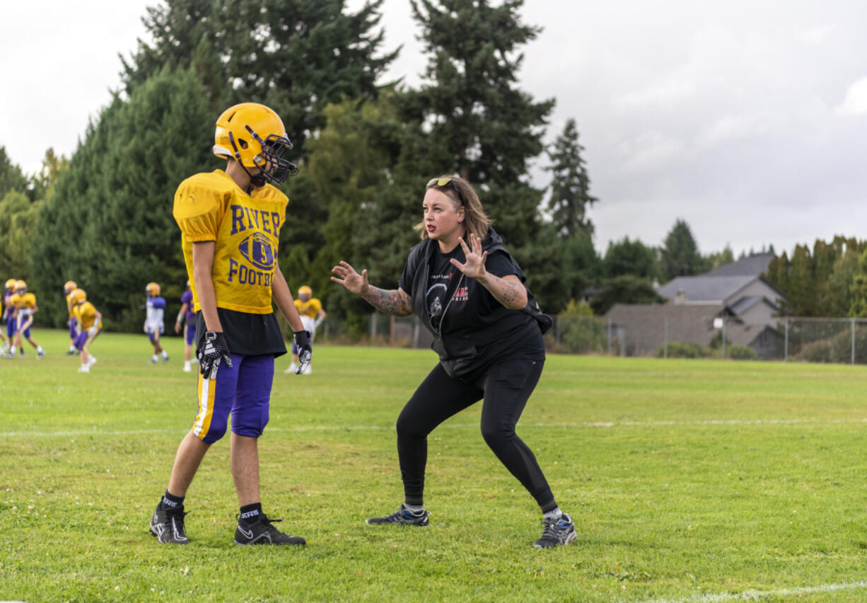 Columbia River assistant defensive coach Ruth Ingebrand, right, coaches a player Tuesday, Sept. 26, 2023, during football practice at Columbia River High School.