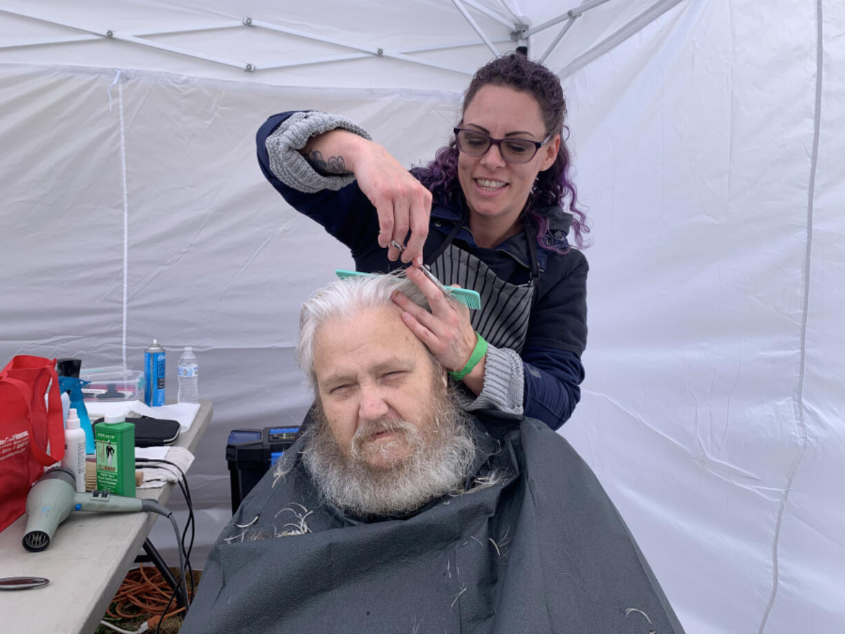 Brian Grose, a veteran who served in the Marine Corps in Hawaii, receives a haircut by hair stylist Sara McHann.