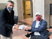 In this photo provided by I AM ALS, Dan Tate, right, delivers a printed petition from ALS patients and advocates to Dr. Peter Marks, left, director of the Food and Drug Administration's center for biologics at the FDA campus in Silver Spring, Md., on Dec. 14, 2022. The FDA meets this week to consider approval of an experimental treatment for Lou Gehrig's disease, the culmination of a yearslong lobbying effort by patients with the fatal, neurodegenerative disease. Those advocates still face one giant hurdle: FDA regulators say the treatment hasn't been shown to work. In documents posted Monday, Sept. 25, 2023 the FDA reiterated its longstanding position: drugmaker Brainstorm's lone study doesn't provide clear evidence that its stem cell-based therapy helps patients with ALS, or amyotrophic lateral sclerosis.