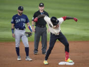 Texas Rangers' Adolis Garcia, right, celebrates his double as Seattle Mariners second baseman Jose Caballero (76) and umpire Mike Muchlinski stand by in the second inning of a baseball game, Saturday, Sept. 23, 2023, in Arlington, Texas.