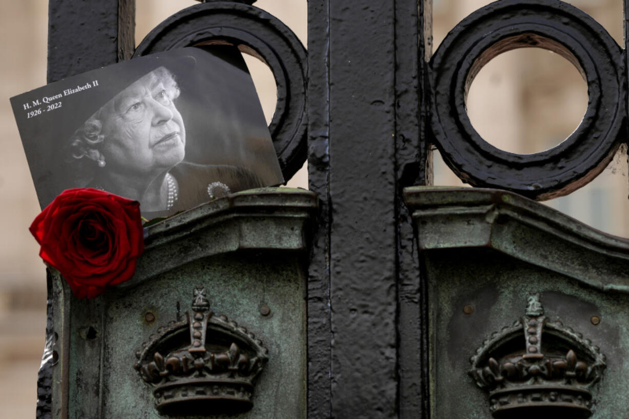 A tribute to Britain's Queen Elizabeth II, is tucked into the gates of Buckingham Palace in London, Friday, Sept. 8, 2023. With gun salutes and tolling bells, Britain is marking the first anniversary of the death of Queen Elizabeth II and the ascension of King Charles III, who remembered his mother as a symbol of stability during her 70-year reign.