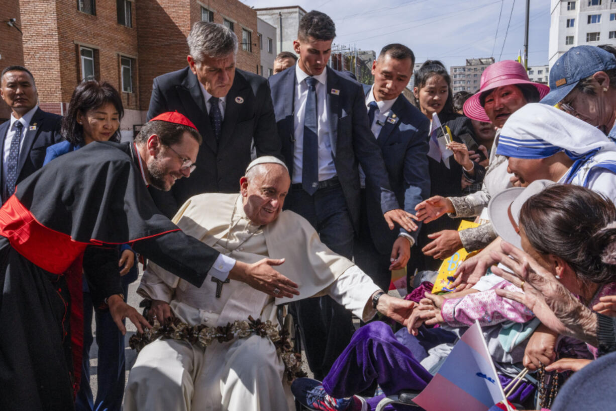 Pope Francis is greeted by Cardinal Giorgio Marengo, left, Apostolic Prefect of Ulaanbaatar, and faithful gathered outside the Apostolic Prefecture in Ulaanbaatar's Kahn Uul district, Friday, Sept. 1, 2023. Pope Francis is traveling to Mongolia to encourage one of the world's smallest and newest Catholic communities. It's the first time a pope has visited the Asian country and comes at a time when the Vatican's relations with Mongolia's two powerful neighbors, Russia and China, are once again strained.