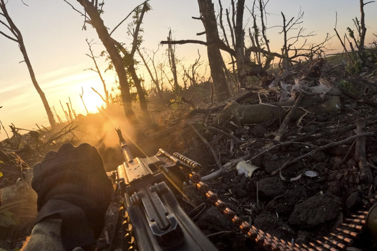 In this image taken from a video released by the 3rd Assault Brigade, a Ukrainian servicemen fires machine gun towards Russian positions near Andriivka, Donetsk region, Ukraine, Aug. 27, 2023. Ukrainian brigade's two-month battle to fight its way through a charred forest shows the challenges of the country's counteroffensive in the east and south.