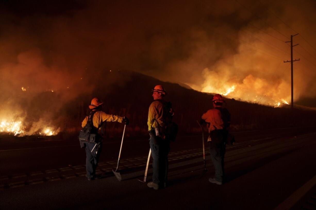 FILE - Firefighters monitor as flames consume brush along Gilman Springs Road during the Rabbit Fire, July 14, 2023, in Moreno Valley, Calif. More Americans believe they've personally felt the impact of climate change because of recent extreme weather according to new polling from The Associated Press-NORC Center for Public Affairs Research.