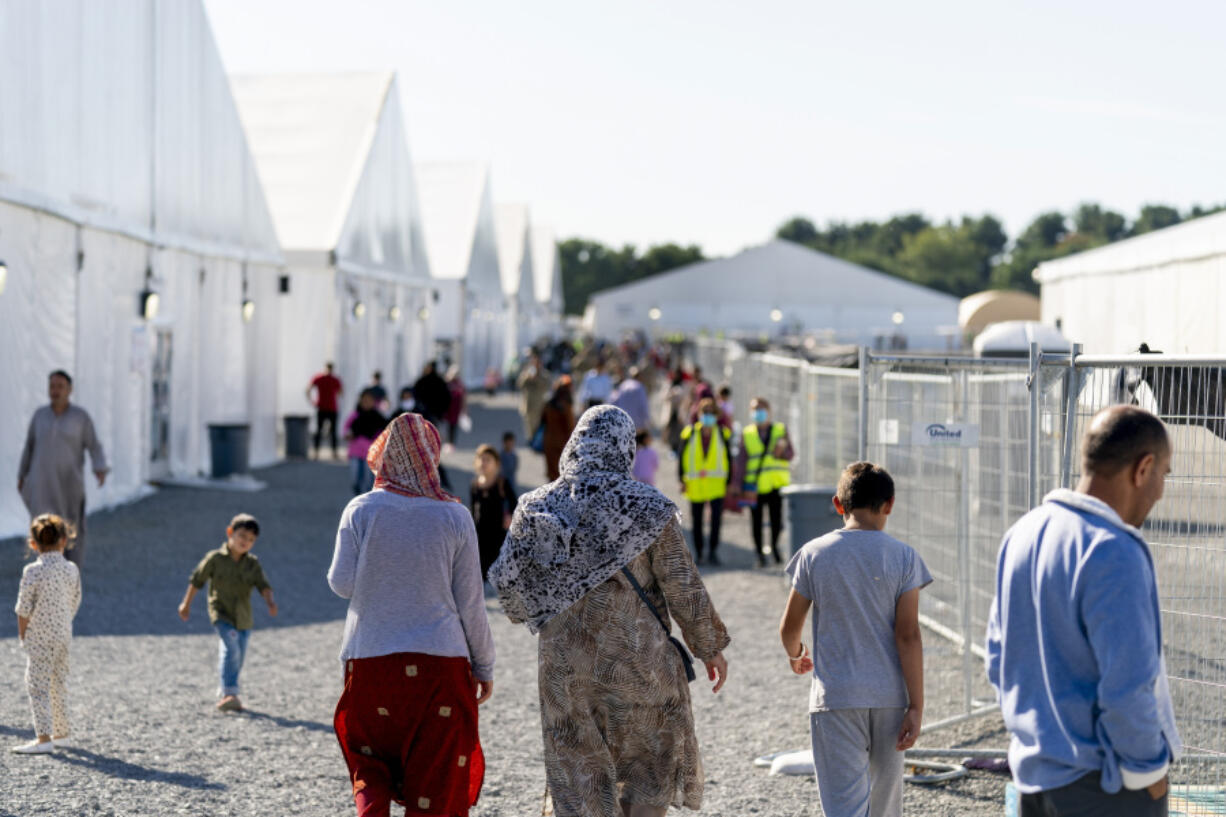 FILE - Afghan refugees walk through an Afghan refugee camp at Joint Base McGuire Dix Lakehurst, N.J., on Sept. 27, 2021. More than 840,000 Afghans who applied for a resettlement program aimed at people who helped the U.S. war effort in Afghanistan are still there waiting, according to a report that lays out the challenges with a program intended to help America's allies in the two-decade long conflict.