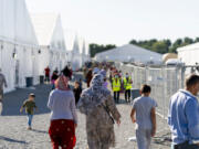 FILE - Afghan refugees walk through an Afghan refugee camp at Joint Base McGuire Dix Lakehurst, N.J., on Sept. 27, 2021. More than 840,000 Afghans who applied for a resettlement program aimed at people who helped the U.S. war effort in Afghanistan are still there waiting, according to a report that lays out the challenges with a program intended to help America's allies in the two-decade long conflict.