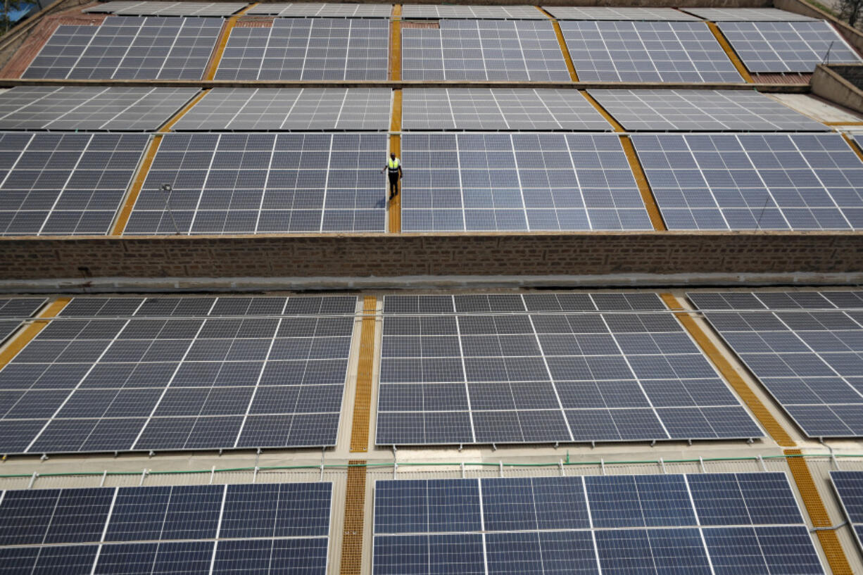 Mark Munyua, CP solar's technician, examines solar panels on the roof of a company in Nairobi, Kenya, Friday, Sept. 1, 2023. Access to electricity remains a major challenge for over half a billion people in sub-Saharan Africa, and power outages are common. In South Africa and Kenya, solar is being used to power major businesses.