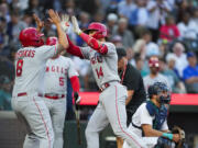 Los Angeles Angels' Logan O'Hoppe (14) is greeted by teammate Mike Moustakas (8) after scoring on his two-run home run off Seattle Mariners starting pitcher Logan Gilbert during the second inning of a baseball game as Mariners catcher Cal Raleigh, right, looks on Monday, Sept. 11, 2023, in Seattle.