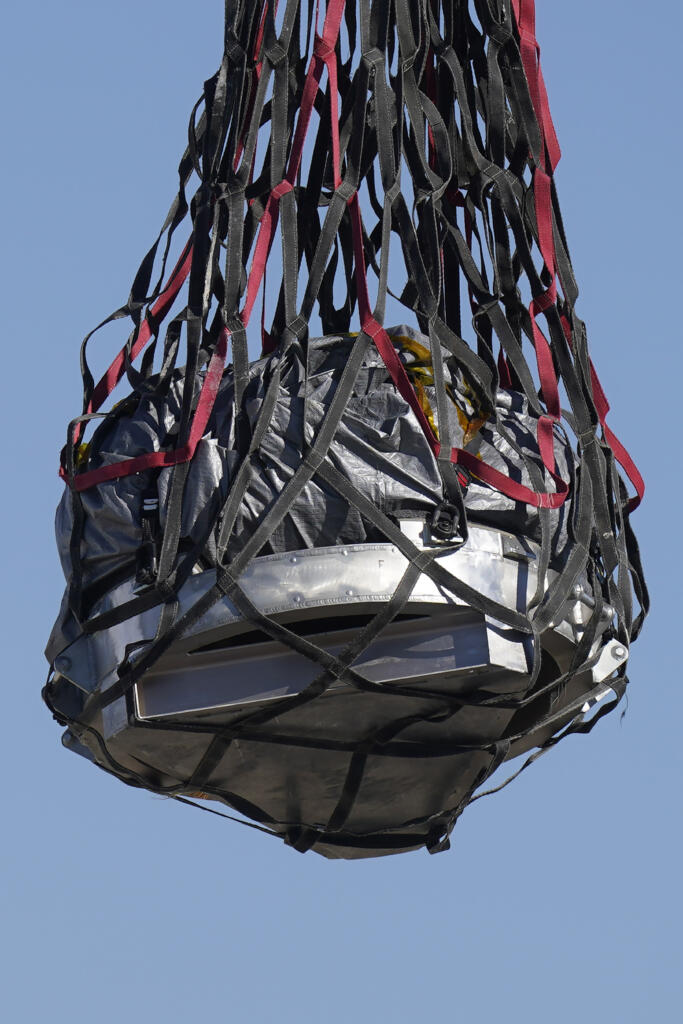 A helicopter delivers a space capsule carrying NASA's first asteroid samples on Sunday, Sept. 24, 2023, to a temporary clean room at Dugway Proving Ground, in Utah. The Osiris-Rex spacecraft released the capsule following a seven-year journey to asteroid Bennu and back.