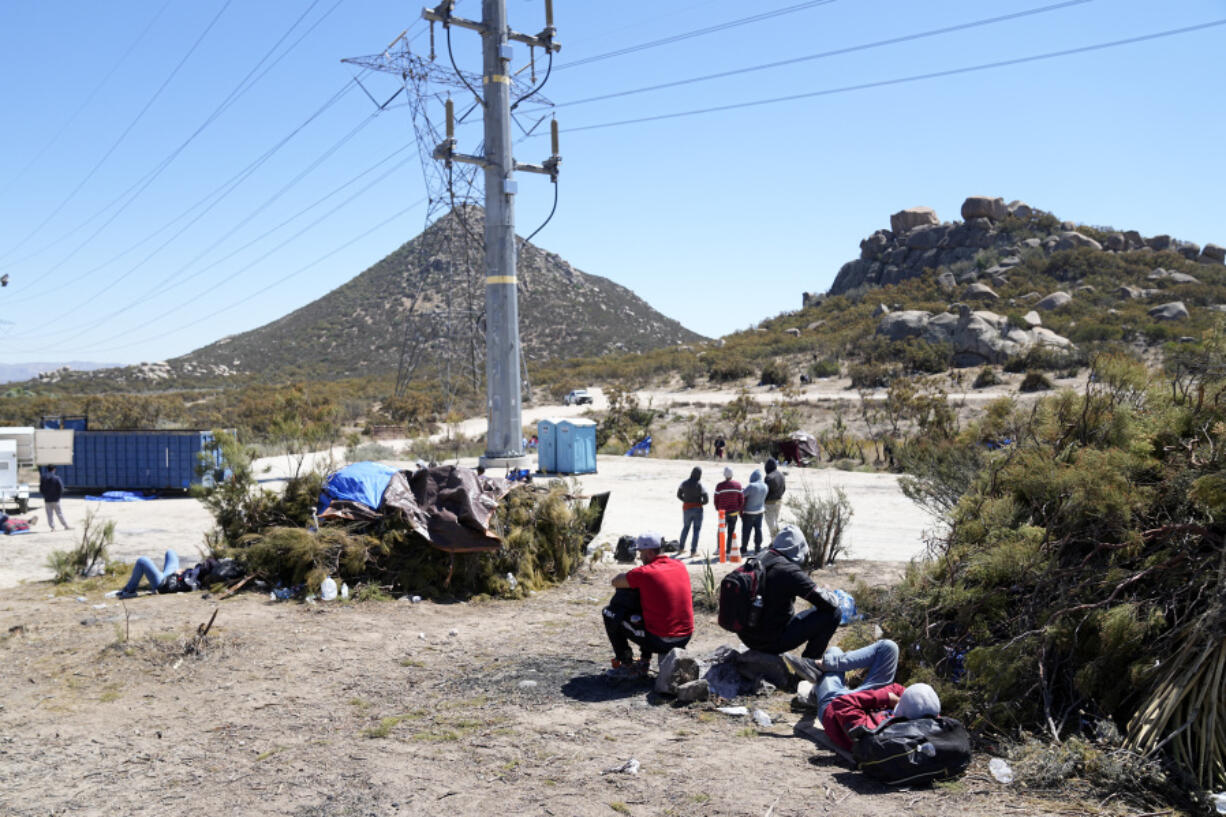 Asylum-seekers wait in a makeshift camp after crossing the nearby border with Mexico, Wednesday, Sept. 20, 2023, near Jacumba Hot Springs, Calif. Migrants continue to arrive to desert campsites along California's border with Mexico, as they await processing in tents made from tree branches.