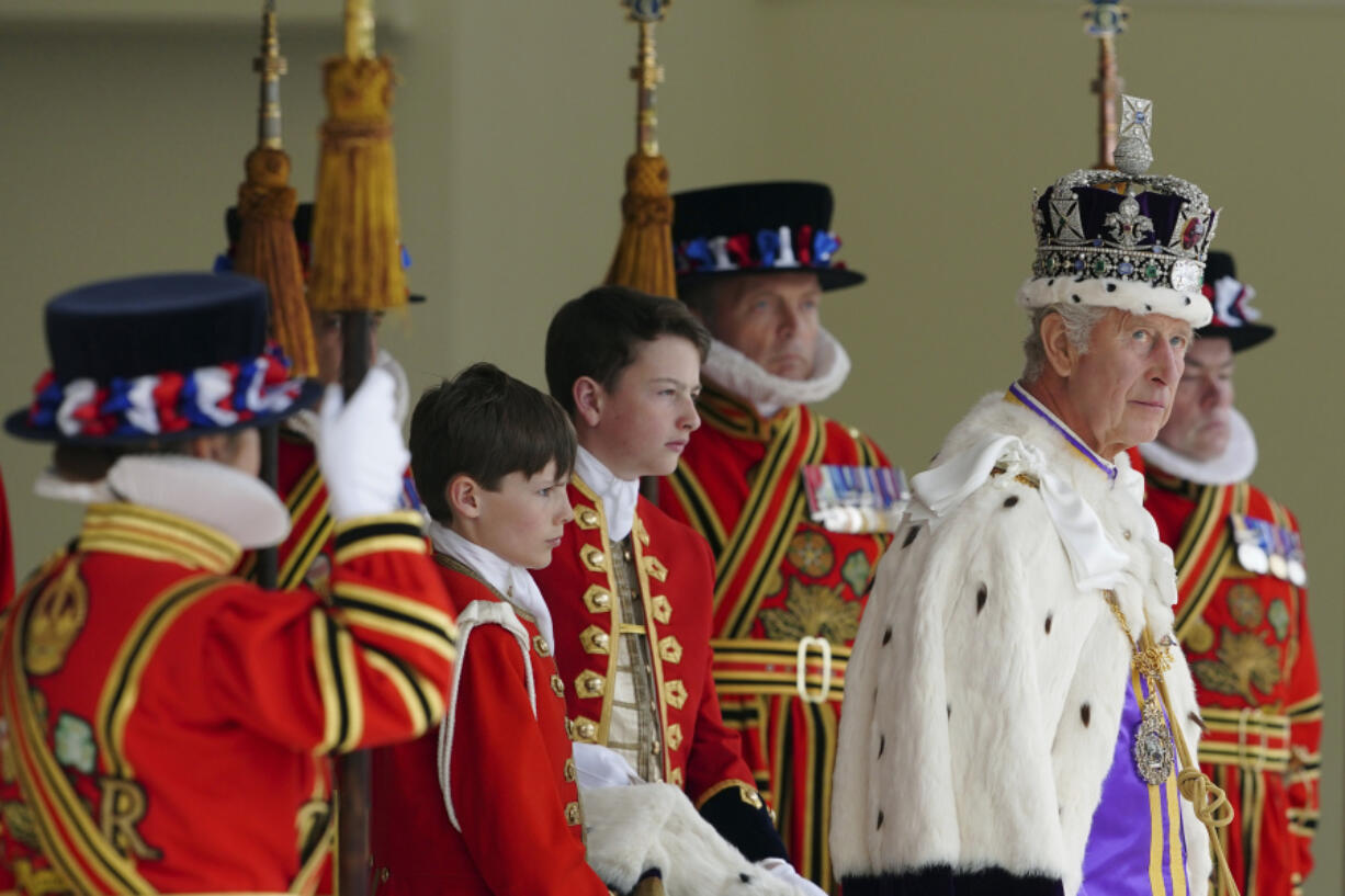 FILE - Britain's King Charles III, right, arrives to receive a royal salute from members of the military in the gardens of Buckingham Palace, following his coronation, in London, Saturday May 6, 2023. A year after the death of Queen Elizabeth II triggered questions about the future of the British monarchy, King Charles III's reign has been marked more by continuity than transformation, by changes in style rather than substance.