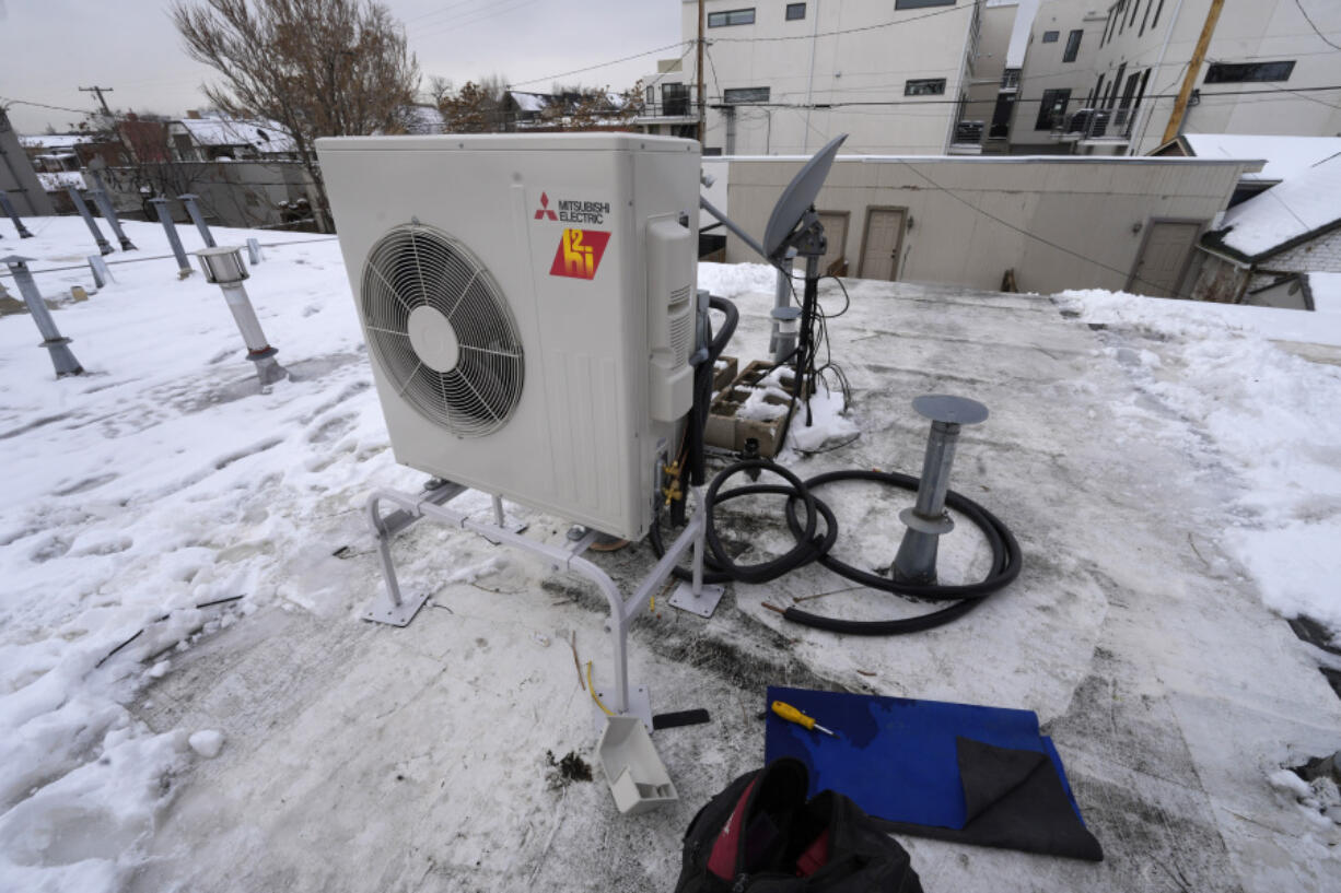 FILE - A condenser sits on the roof during the installation of a heat pump on Jan. 20, 2023, in Denver. A bipartisan coalition of about 25 governors and the Biden administration are set to announce a pledge Thursday, Sept. 21, 2023, to quadruple the number of heat pumps in U.S. homes by 2030.