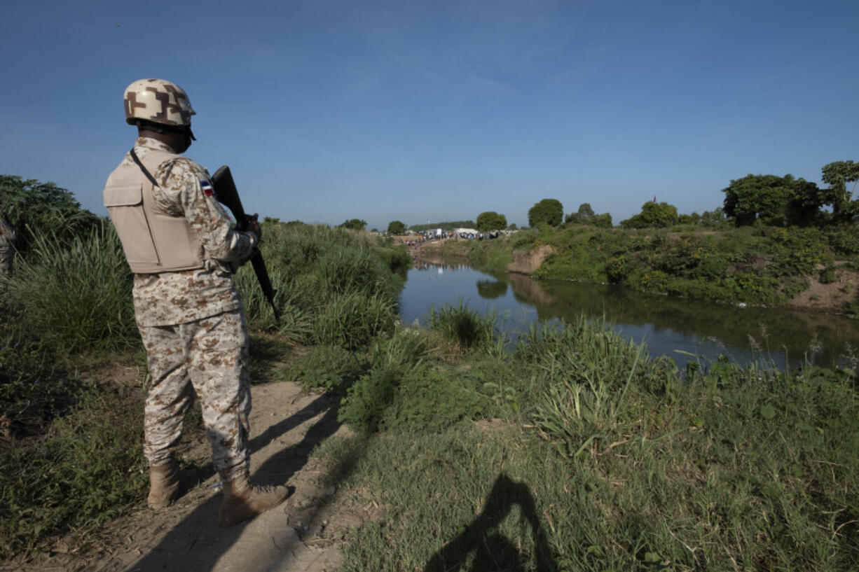 A Dominican Republic soldier stands on the bank of the Massacre River, a natural border with Haiti, down river from the construction of a canal on the Haitian side, in Dajabon, Dominican Republic, Friday, Sept. 15, 2023. The Dominican Republic shut all land, air and sea borders with Haiti on Friday in a dispute about construction of a canal on Haitian soil that taps into the shared river.