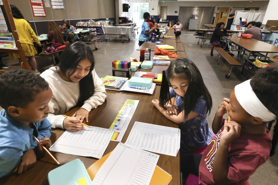 Ayub Mohamed, 7, gets help from volunteer tutor Esmeralda Jimenez, 13, while Olivia Elaydo, 7, and Eden Pollard, 6, work on math problems during a summer tutoring program with School Connect WA at Dearborn Park International Elementary School in Seattle on July 28, 2023.