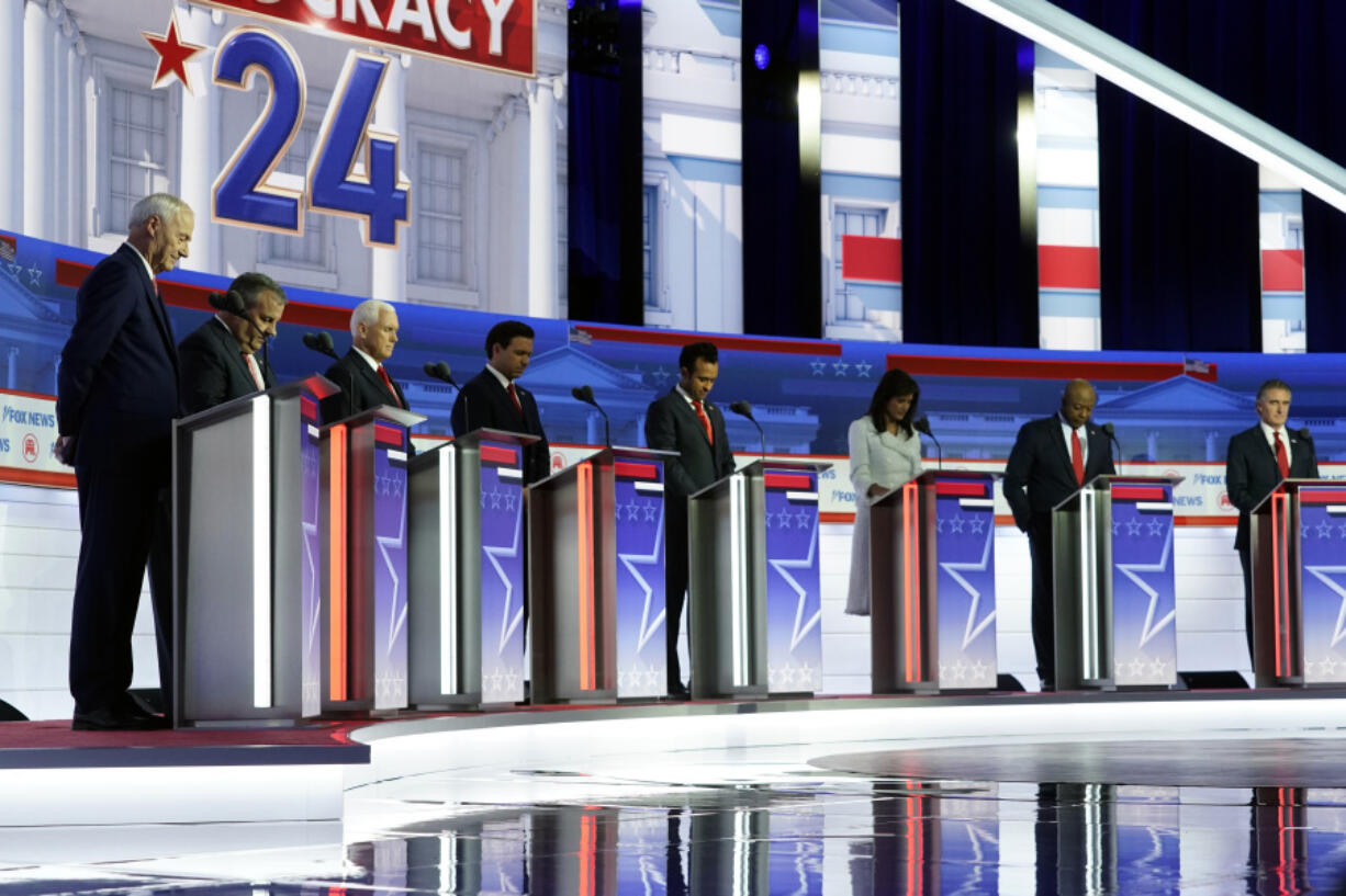 FILE - Republican presidential candidates, from left, former Arkansas Gov. Asa Hutchinson, former New Jersey Gov. Chris Christie, former Vice President Mike Pence, Florida Gov. Ron DeSantis, businessman Vivek Ramaswamy, former U.N. Ambassador Nikki Haley, Sen. Tim Scott, R-S.C., and North Dakota Gov. Doug Burgum stand on stage and listen to a prayer before a Republican presidential primary debate hosted by FOX News Channel, Wednesday, Aug. 23, 2023, in Milwaukee.