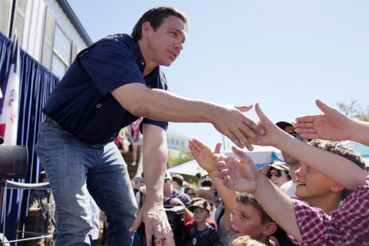 FILE - Republican presidential candidate Florida Gov. Ron DeSantis shakes hands with fairgoers after taking part in a Fair-Side Chat with Iowa Gov. Kim Reynolds at the Iowa State Fair, Saturday, Aug. 12, 2023, in Des Moines, Iowa. Republicans are responding to a late summer spike in COVID-19 by raising familiar fears that government-issued lockdowns and mask mandates are on the horizon. GOP presidential hopefuls including Florida Gov. Ron DeSantis, South Carolina Sen. Tim Scott and former President Donald Trump have spread this narrative.