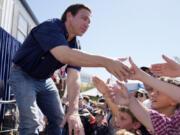 FILE - Republican presidential candidate Florida Gov. Ron DeSantis shakes hands with fairgoers after taking part in a Fair-Side Chat with Iowa Gov. Kim Reynolds at the Iowa State Fair, Saturday, Aug. 12, 2023, in Des Moines, Iowa. Republicans are responding to a late summer spike in COVID-19 by raising familiar fears that government-issued lockdowns and mask mandates are on the horizon. GOP presidential hopefuls including Florida Gov. Ron DeSantis, South Carolina Sen. Tim Scott and former President Donald Trump have spread this narrative.