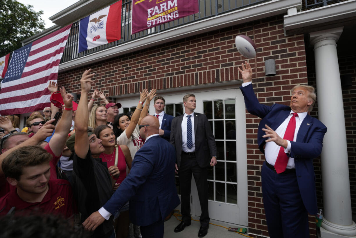 Former President Donald Trump throws a football to the crowd during a visit to the Alpha Gamma Rho, agricultural fraternity, at Iowa State University before an NCAA college football game between Iowa State and Iowa, Saturday, Sept. 9, 2023, in Ames, Iowa.