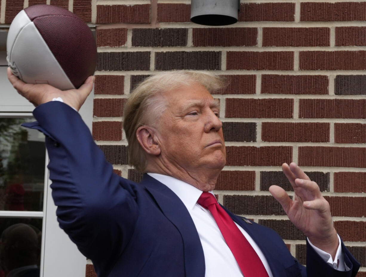 Former President Donald Trump throws a football to the crowd during a visit to the Alpha Gamma Rho, agricultural fraternity, at Iowa State University before an NCAA college football game between Iowa State and Iowa, Saturday, Sept. 9, 2023, in Ames, Iowa.