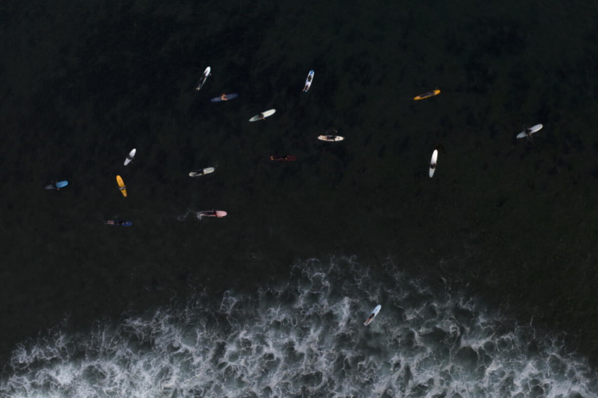 FILE - Surfers float in the water while waiting for a wave in Malibu, Calif., Aug. 31, 2023. Earth is exceeding its "safe operating space for humanity" in six of nine key measurements of its health, and two of the remaining three, one being ocean acidity, are headed in the wrong direction, a new study said. (AP Photo/Jae C.