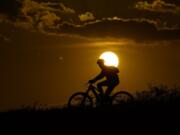 FILE - A cyclist tops a hill on a hot day at sunset, Aug. 20, 2023, in San Antonio. UN weather agency says Earth sweltered through the hottest summer ever as record heat in August capped a brutal, deadly three months in northern hemisphere.