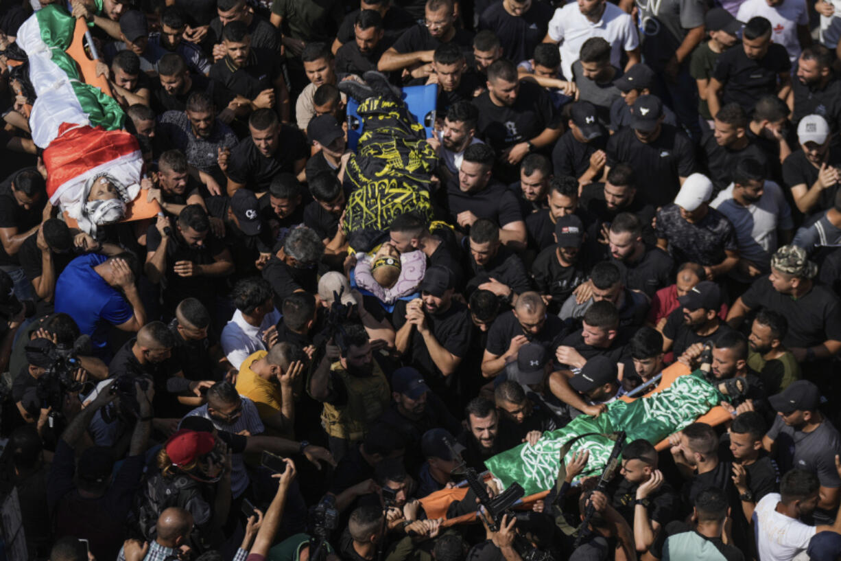 Mourners carry the bodies of Mahmoud al-Sadi, 23, Mahmoud Ararawi, 24, and Ata Yasser Musa, 29, draped in the Hamas and Islamic Jihad militant group flags during their funeral in the Jenin refugee camp, West Bank, Wednesday, Sept. 20, 2023. Palestinian health officials say the death toll over a day of fighting between Israel and the Palestinians in the occupied West Bank and the Gaza Strip has risen to six, four from Jenin. The army said that forces carried out a rare strike Tuesday with a suicide drone during the operation and exchanged fire with gunmen in Jenin.