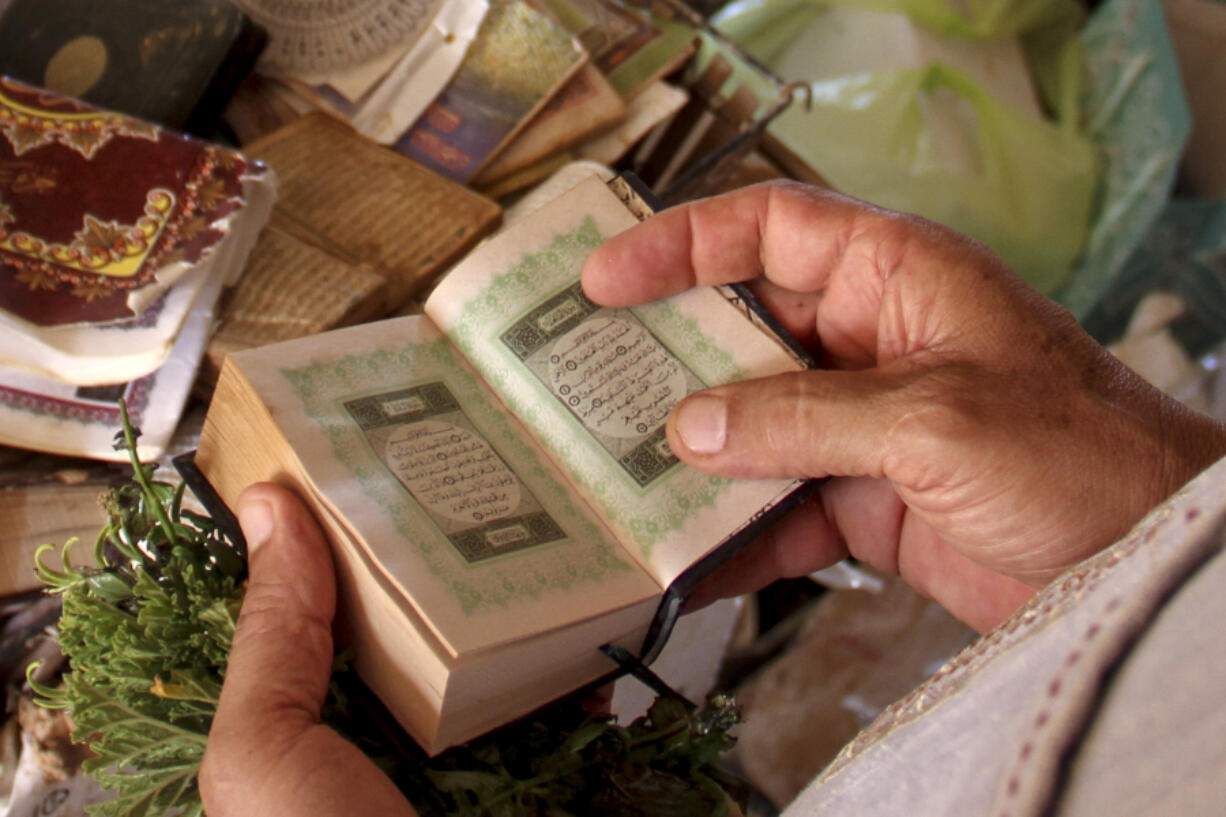 Derna flood survivor Abdul Salam Anwisi holds a copy of the Quran, Muslims' holy book, at his damaged home following flooding caused by Mediterranean storm Daniel, in Derna, Libya, Sunday, Sept. 17, 2023. Anwisi said he woke up at one-thirty in the morning to a scream from outside to find his neighbours' homes flooded with water. He, his sons, and other neighbours rushed to rescue the stranded families by pulling them from the roof of their house. Thousands of Libyans have lost  family members, friends and neighbors in the devastating floods that engulfed the country's east.