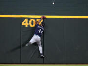 Seattle Mariners' Julio Rodriguez slams against the wall after attempting to make a play on a home run ball hit by Texas Rangers' Leody Taveras in the fourth inning of a baseball game, Sunday, Sept. 24, 2023, in Arlington, Texas.