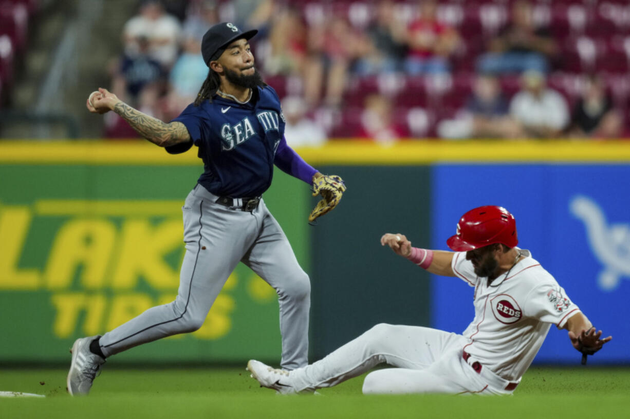 Seattle Mariners' J.P. Crawford, left, forces out Cincinnati Reds' Nick Martini at second base as he throws to first base to complete the double play during the eighth inning of a baseball game in Cincinnati, Wednesday, Sept. 6, 2023.