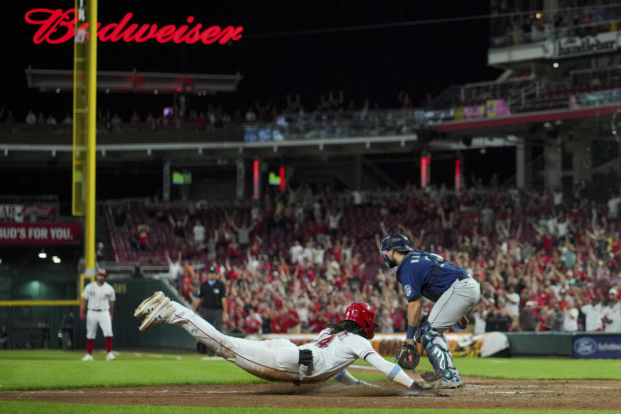 Cincinnati Reds' Elly De La Cruz, center, scores the game-winning run on a single by Christian Encarnacion-Strand during the ninth inning of a baseball game against the Seattle Mariners in Cincinnati, Tuesday, Sept. 5, 2023.