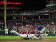 Cincinnati Reds' Elly De La Cruz, center, scores the game-winning run on a single by Christian Encarnacion-Strand during the ninth inning of a baseball game against the Seattle Mariners in Cincinnati, Tuesday, Sept. 5, 2023.