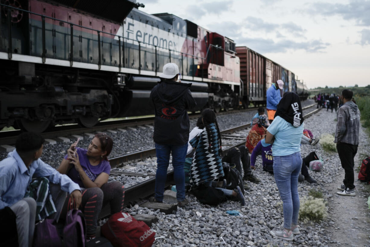 Migrants watch a train go past as they wait along the train tracks hoping to board a freight train heading north, in Huehuetoca, Mexico, Sept. 19, 2023. Ferromex, Mexico's largest railroad company announced that it was suspending operations of its cargo trains due to the massive number of migrants that are illegally hitching a ride on its trains moving north towards the U.S. border.