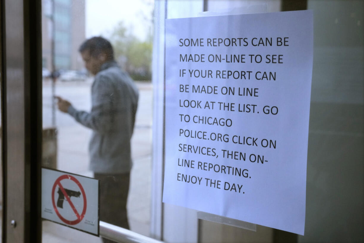 FILE - A migrant from Venezuela talks outside on a cell phone where he has taken shelter with others in the Chicago Police Department's 16th District station on Monday, May 1, 2023. In Chicago, where 13,000 migrants have settled in the last year, Mayor Brandon Johnson and Illinois Gov. J.B. Pritzker wrote Homeland Security Secretary Alejandro Mayorkas to ask for parole for asylum-seekers, which, they say, would allow him to get around the wait for a work permit.