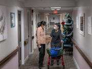 FILE - Tina Sandri, CEO of Forest Hills of DC senior living facility, left, helps resident Courty Andrews back to her room, Dec. 8, 2022, in Washington. The federal government will, for the first time, dictate staffing levels at nursing homes, the Biden administration said Friday, Sept. 1, 2023, responding to systemic problems bared by mass COVID deaths.