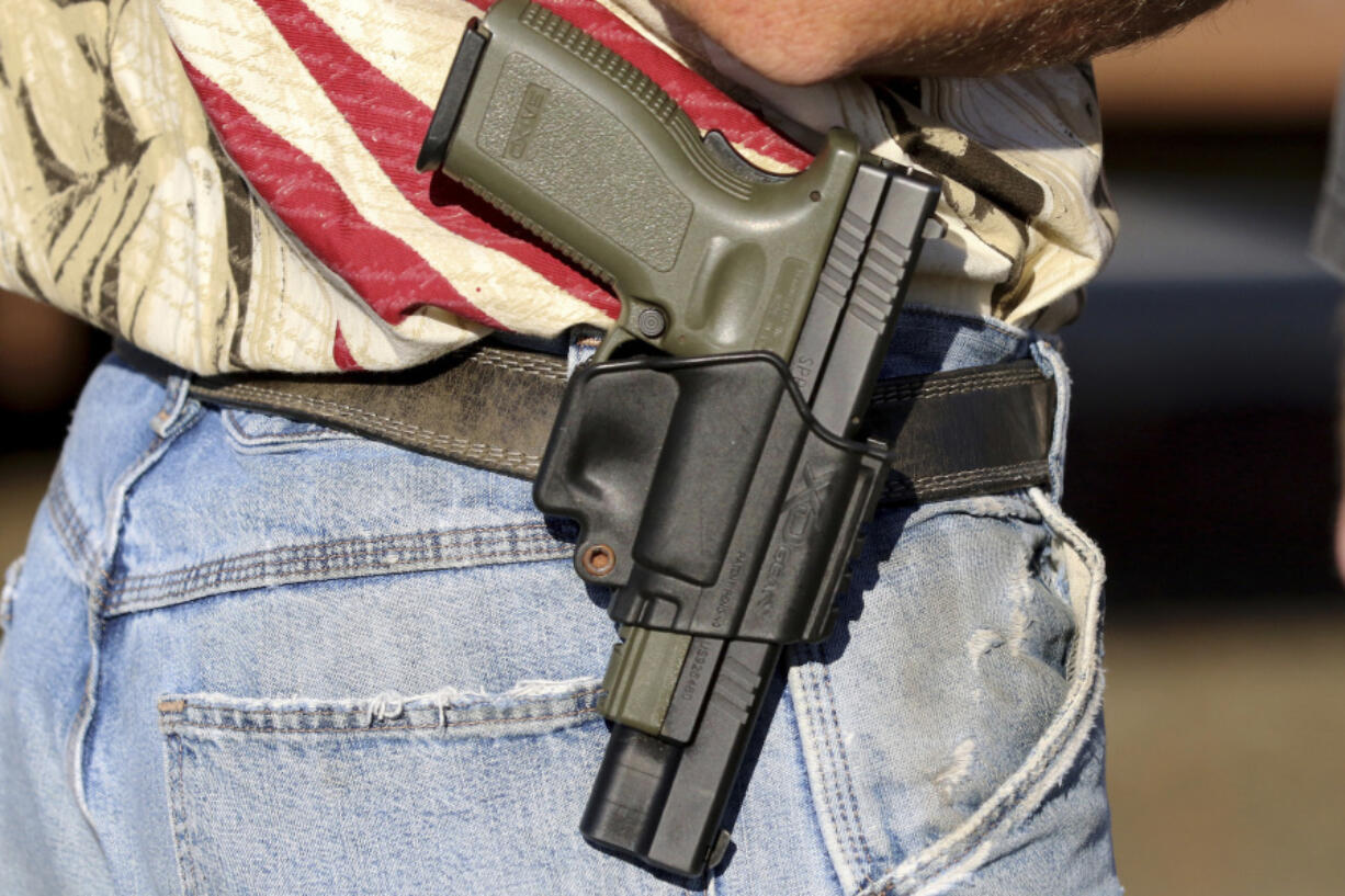 FILE - In this Oct. 9, 2015 file photo, Michael Johnson wears a firearm as he waits outside of Roseburg Municipal Airport for President Barack Obama's arrival in Roseburg, Ore. An Oregon judge will decide during a trial starting Monday, Sept. 18, 2023 whether a gun control law approved by voters last year is lawful under the state constitution.