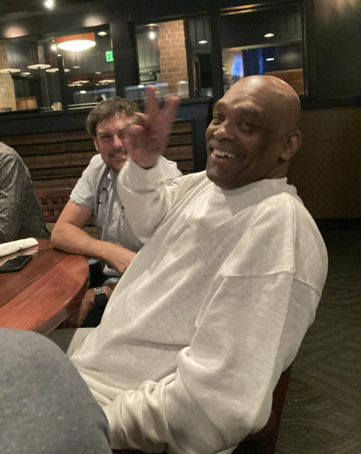 In this photo provided by John Lewis, Jesse Johnson gestures while sitting with James Comstock in Lake Oswego, Ore., on Tuesday, Sept. 5, 2023. Johnson, convicted of a 1998 murder and sentenced to death, is now free, two years after the Oregon Court of Appeals reversed the conviction on Tuesday. Prosecutors asked for the case to be dismissed, saying that with the passage of time, the state no longer believes that it can prove Johnson was guilty. Johnson has always maintained his innocence.