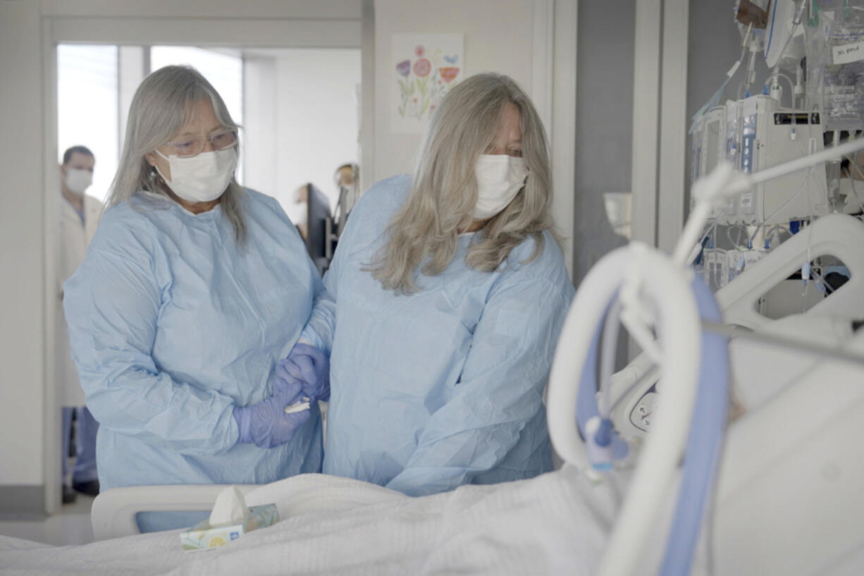 Relatives of Maurice "Mo" Miller, Mary Miller-Duffy, his sister, right, and her wife, Sue Duffy, stand with his body at NYU Langone Health in New York on Tuesday, Sept. 12, 2023. "I'm so proud of you," Miller-Duffy said in a tearful farewell. For a history-making 61 days and despite a brief rejection blip, a pig's kidney worked normally inside his brain-dead body.