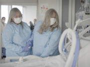 Relatives of Maurice "Mo" Miller, Mary Miller-Duffy, his sister, right, and her wife, Sue Duffy, stand with his body at NYU Langone Health in New York on Tuesday, Sept. 12, 2023. "I'm so proud of you," Miller-Duffy said in a tearful farewell. For a history-making 61 days and despite a brief rejection blip, a pig's kidney worked normally inside his brain-dead body.