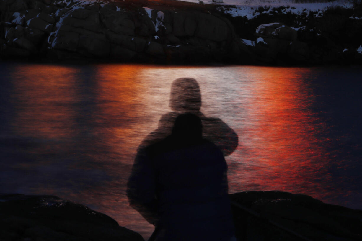 FILE - In this photo made with a long exposure, a man is silhouetted against lights reflected in the waters off Cape Neddick in Maine on Dec. 11, 2017. A study published Thursday, Sept. 14, 2023, in the journal Nature Medicine has found that the psychedelic drug MDMA, combined with talk therapy, can reduce symptoms of post-traumatic stress disorder. (AP Photo/Robert F.