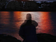 FILE - In this photo made with a long exposure, a man is silhouetted against lights reflected in the waters off Cape Neddick in Maine on Dec. 11, 2017. A study published Thursday, Sept. 14, 2023, in the journal Nature Medicine has found that the psychedelic drug MDMA, combined with talk therapy, can reduce symptoms of post-traumatic stress disorder. (AP Photo/Robert F.