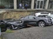 Rick Durand Owner of Durand Cadillac, left, and colleagues stand behind three vehicles that fell into a sinkhole that was washed out of his car dealership Tuesday, Sept. 12, 2023, in Leominster, Mass. after more than 9 inches of rain fell overnight.