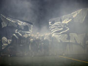 Members of the Skyview football team break through a banner as they take the field at Kiggins Bowl for their game against Jesuit on Sept. 1, 2023.