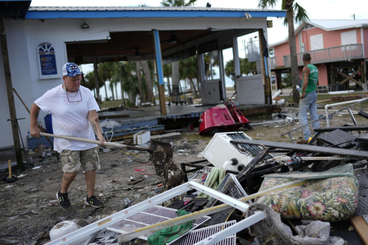 Employee Lisa Bell dumps out a shovel full of mud as business owners and employees start cleaning up at the storm-damaged business The Marina, in Horseshoe Beach, Fla., Thursday, Aug. 31, 2023, one day after the passage of Hurricane Idalia.